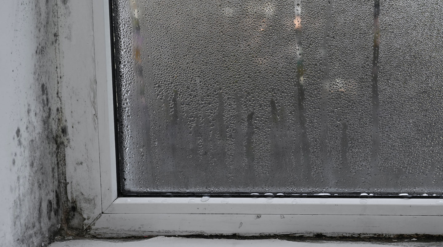 Gros plan détaillé sur des gouttelettes de condensation sur une surface de verre de fenêtre avec arrière-plan intérieur moderne flouté